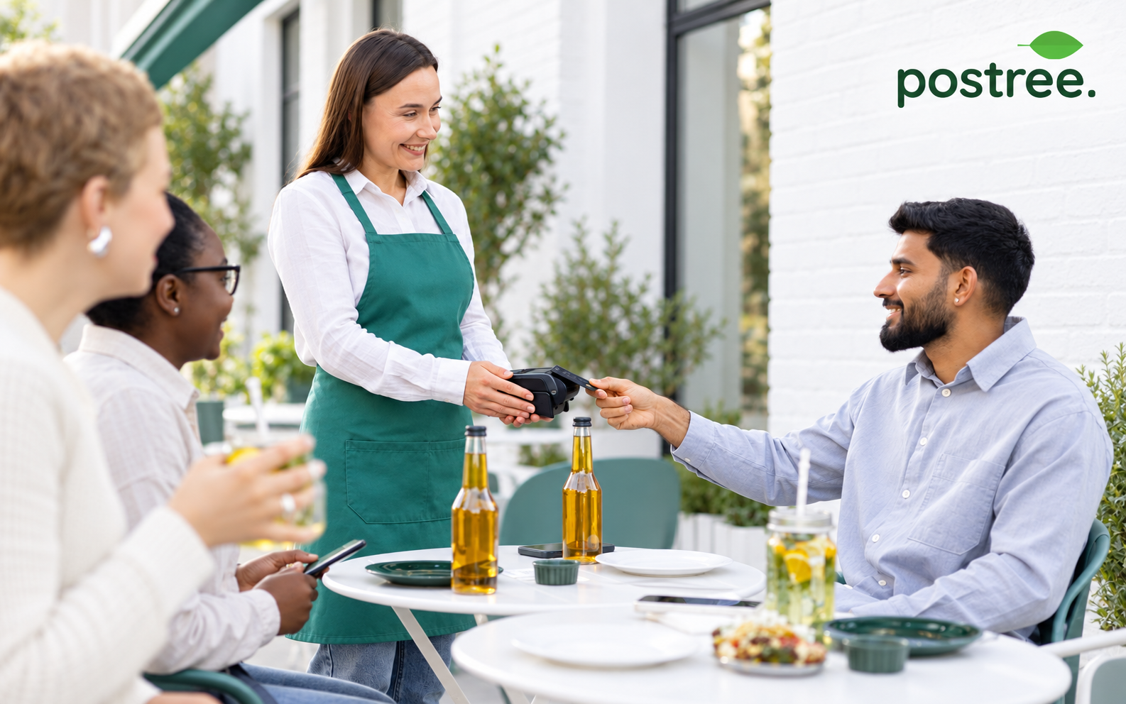 A waiter taking a card payment from a seated guest at a restaurant table